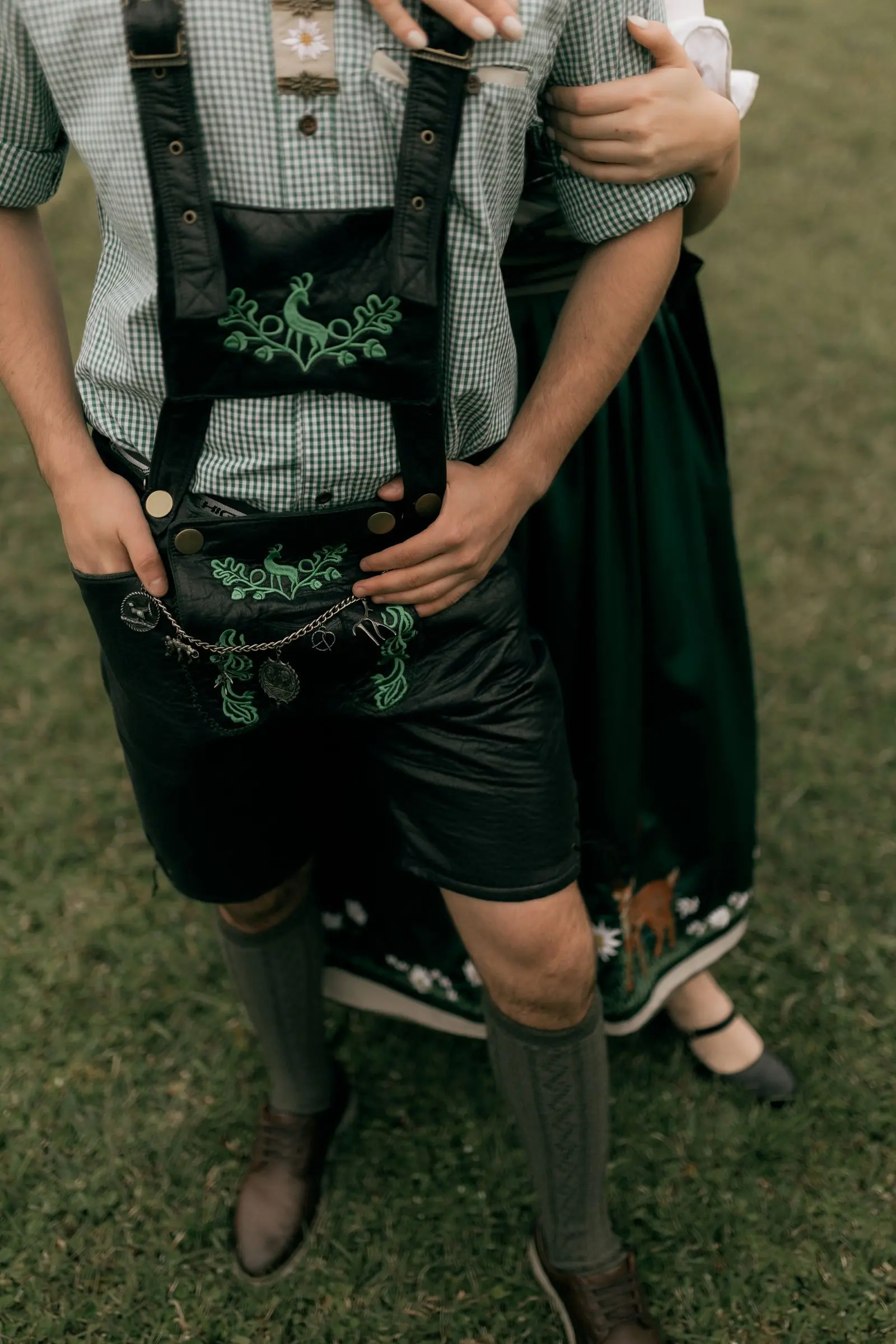 Detalhe de trajes típicos: calça de couro bordada (lederhosen) e vestido tradicional sobre gramado