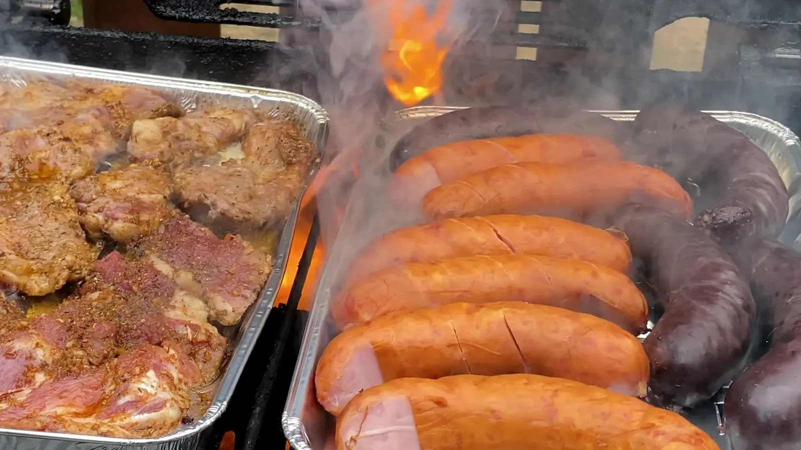 Linguiças e carnes temperadas na grelha, com fogo e fumaça