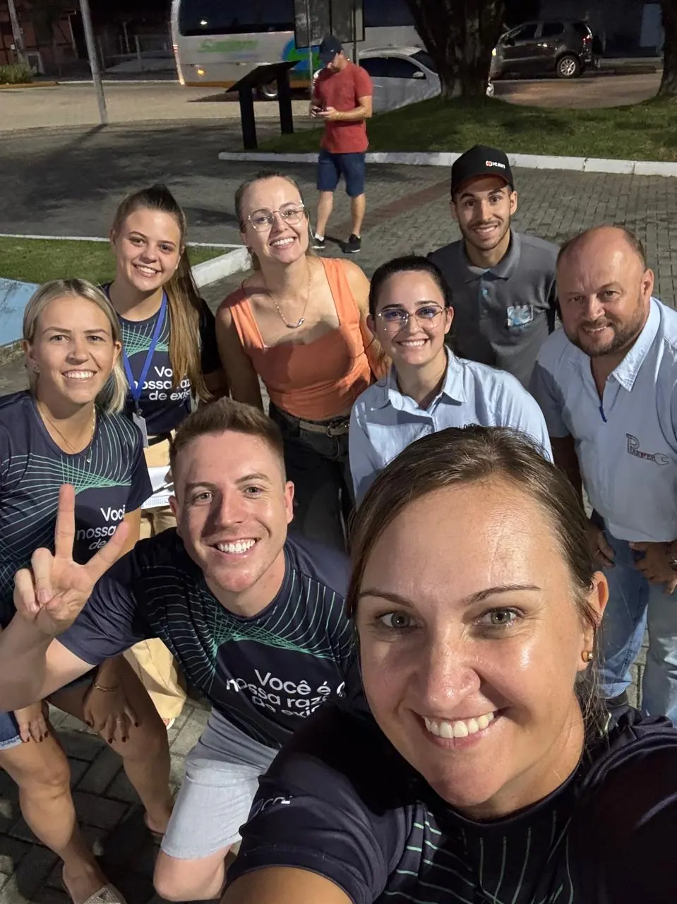 Integrantes da equipe e parceiros do festival sorriem juntos à noite na praça